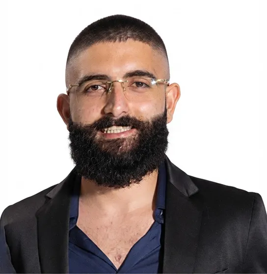 Retrato de Gabriel Mizael, de terno escuro e camisa azul, sorrindo.